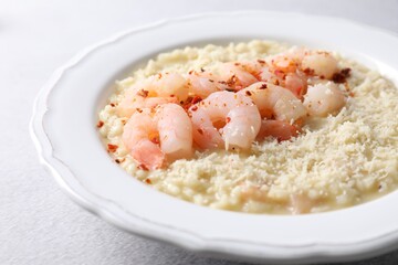 Delicious risotto with shrimps and cheese on light grey table, closeup