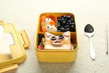 Lunch box with snacks, spoon and chopstick on beige textured table