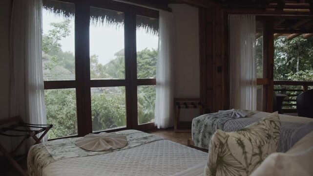 Pan from behind beds to show room of a private cabin in an eco lodge in rainforest