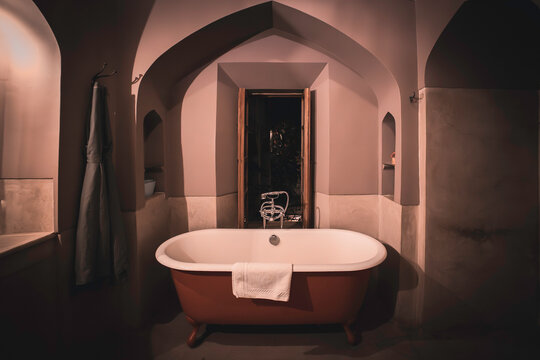 Elegant luxury Vintage Moroccan riad Bathroom with Freestanding Rolltop Bathtub, stylish, dimly lit elegant arch design, moody atmosphere, luxury lifestyle hotel travel aesthetic, Marrakech, Morocco