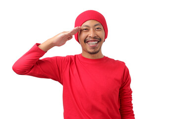 Young Indonesian man wearing a red long sleeve T-Shirt and beanie gives a salute gesture while celebrating Indonesian Independence Day on August 17, Isolated on a white background