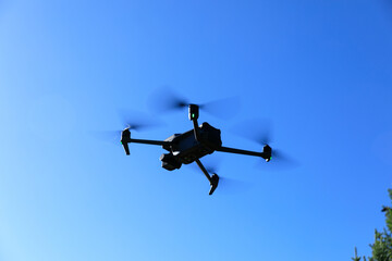 Black drone flying in sunrise blue sky