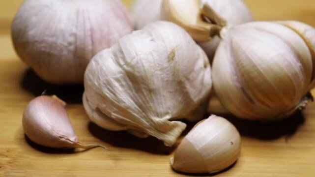 Whole garlic and peeled garlic top view rotate on chopping board footage. garlic rotating on a white background. Pile of garlic top view.

