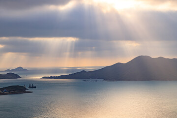 Sunbeams Through Clouds Over Serene Coastal Waters and Distant Islands