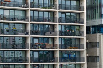 A modern multi-story apartment building with balconies adorned with plants, depicting urban living and the integration of greenery within concrete spaces for a balanced lifestyle.