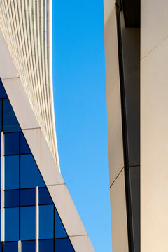 This image depicts a close-up of modern architectural structures with a geometry blend, where sleek lines and angles converge against the backdrop of a clear sky.