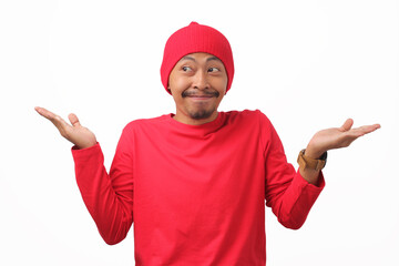 Naklejka premium Cheerful Indonesian man wearing a red shirt and beanie extends both palms outward, offering options or choices during Indonesia's Independence Day celebration on August 17 isolated on white background