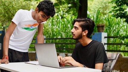 Indian School kids E-learning using laptop. Children doing homework at garden in computer.