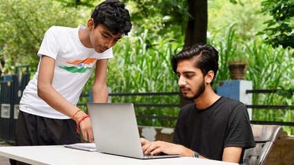 Indian School kids E-learning using laptop. Children doing homework at garden in computer.