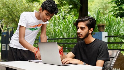Indian School kids E-learning using laptop. Children doing homework at garden in computer.