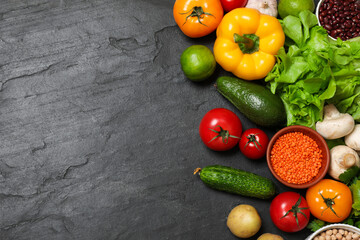 Healthy vegetarian food. Different vegetables, lentils and lime on dark textured table, flat lay. Space for text