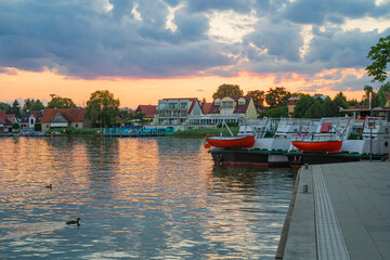 Widok na Zachód Słońca nad Jeziorem w Mikołajkach - Łodzie i Promenada   Scenic Lakeside Sunset in Mikołajki - Boats and Promenade View © Adrian White