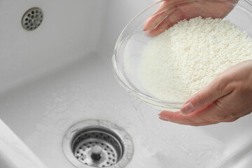 Woman rinsing rice in bowl above sink, closeup
