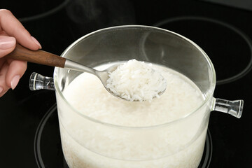 Woman taking boiled rice from pot, closeup