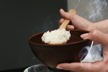 Woman taking boiled rice into bowl, closeup