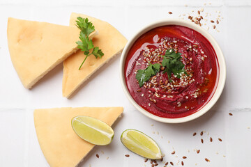 Tasty beetroot hummus in bowl and products on white table, flat lay