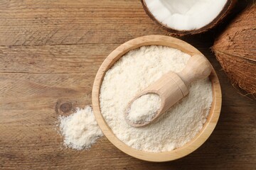 Coconut flour in bowl, scoop and fresh fruits on wooden table, flat lay. Space for text