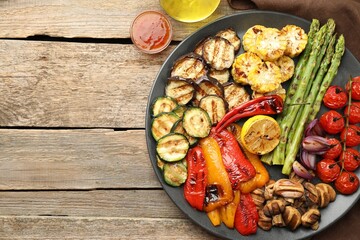 Delicious grilled vegetables served on wooden table, flat lay. Space for text