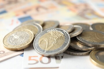 Many coins on euro banknotes, closeup view