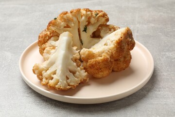 Delicious baked cauliflower on gray textured table, closeup