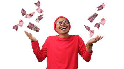 Asian man stands with Indonesian Rupiah banknotes flying around him, creating a money shower effect against a white background. Concept of financial success, prosperity, and Indonesia Independence Day