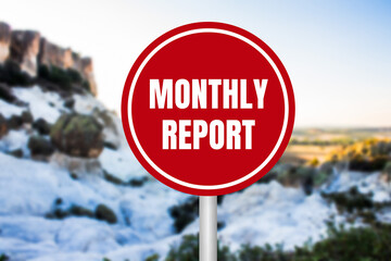 Monthly report message written on red round sign on nature background. Conceptual monthly report...