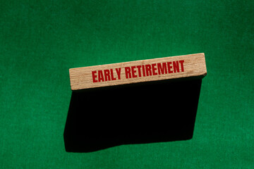 Early retirement message written on wooden block with green background. Conceptual early retirement symbol. Copy space.