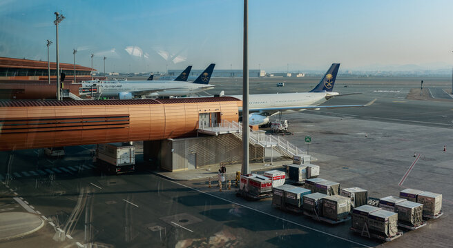 Jeddah, Saudi Arabia - April 29, 2024: Airplanes parked at Jeddah Airport during the afternoon with cargo containers in view