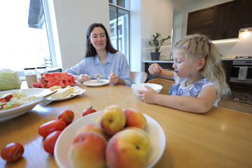Mother and a small daughter cooking food at home in the kitchen