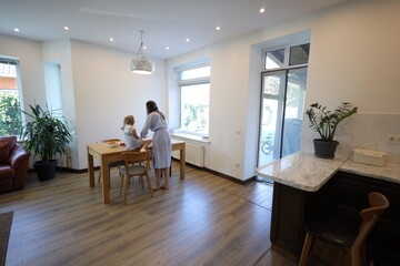 Mother and a small daughter cooking food at home in the kitchen