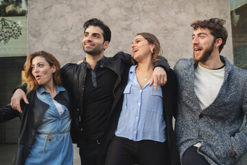 Diverse group of young friends laughing together outdoors, millennials lifestyle and friendship concept