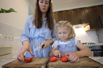 Mother and a small daughter cooking food at home in the kitchen