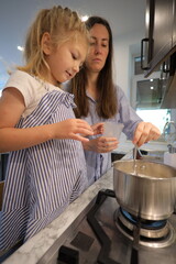 Mother and a small daughter cooking food at home in the kitchen