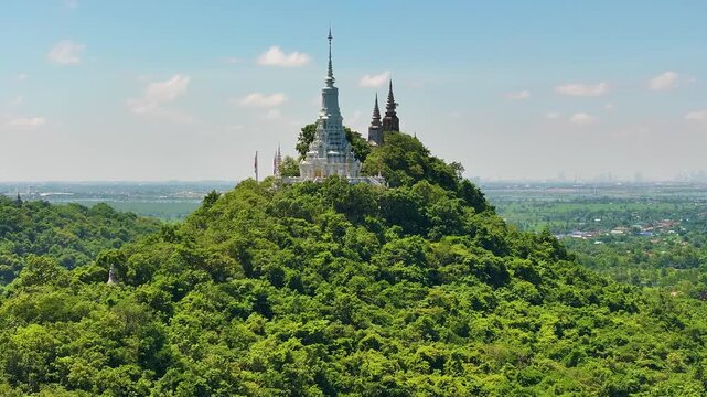 A close-up view of a Buddhist stupa is located on top of the Oudong mountain, the old city of Cambodia. cover with a green fields