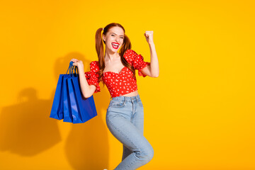 Photo portrait of attractive young woman hold shopping bags winning dressed stylish red retro clothes isolated on yellow color background