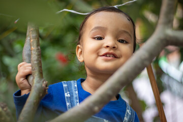 innocent toddler holding tree branch with cute facial expression at day from flat angle