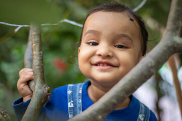 innocent toddler holding tree branch with cute facial expression at day from flat angle