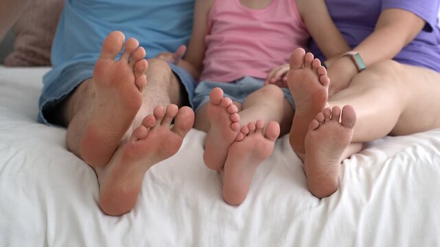 Three barefoot people, mother, father and daughter resting on the sofa, foot closeup, corns and calluses on feet, dry skin on legs, cracked heels, body care concept