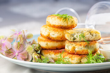 Fried cottage cheese pancakes syrniki with dill and asparagus on a blue plate served with sour cream and wine.
