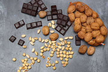 Homemade chocolate ingredients on a table. Nuts and chocolates close up photo. Dark chocolate, pistachio, walnut and hazelnut against dark background with space for text. 