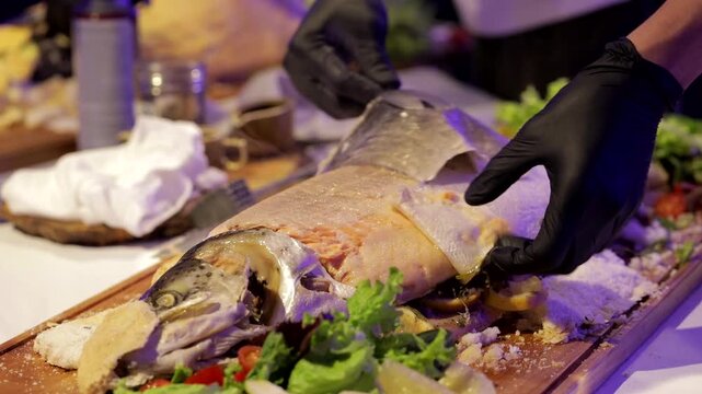 The waiter places baked fish on the dishes