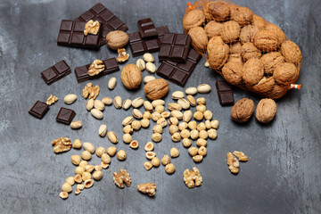Homemade chocolate ingredients on a table. Nuts and chocolates close up photo. Dark chocolate, pistachio, walnut and hazelnut against dark background with space for text. 
