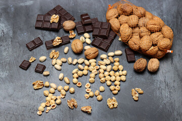 Chocolate bars, walnuts and hazelnuts on a gray background.
