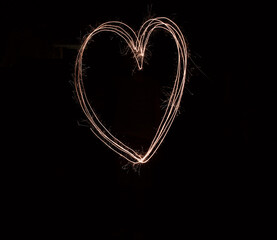 Fireworks, heart and sparkler with black background for celebration, love or romance on valentines day. Gold, new year and party with magic light shape in dark for evening, holiday or night event