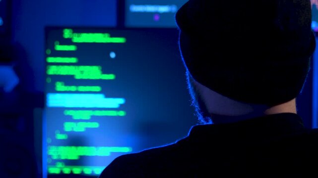 Computer hacker tying code onto a screen