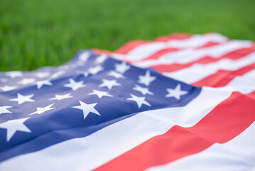 Close up of stars and stripes of American flag, green fresh grass on the background. USA banner...