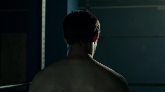 Back view chest up shot in lowkey of athletic man doing scapular upward rotation exercise while training at gym