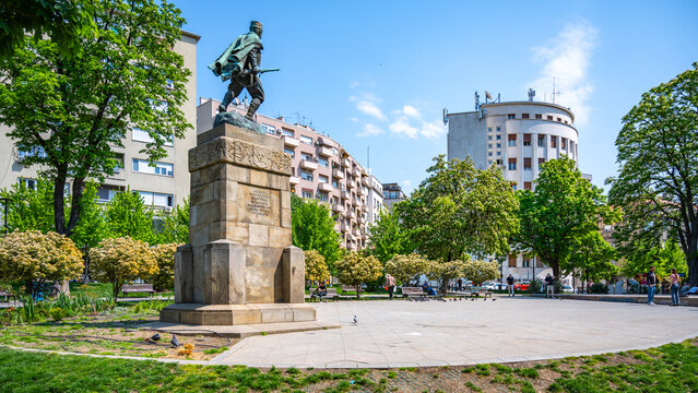 Vojvoda Vuk Park in Belgrade features a prominent statue amidst lush greenery, with visitors enjoying the space under a clear blue sky on a beautiful day.