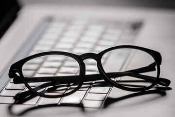 Stylish glasses rest on a laptop keyboard, providing essential eye protection during extended computer use. Ideal for reducing digital eye strain during long hours of screen time.