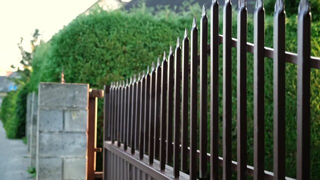 Opening of automatic entrance gate of brown color made of metal. Block fence. Entrance group for cars in the private house. Remote control. Smart home system. Close-up